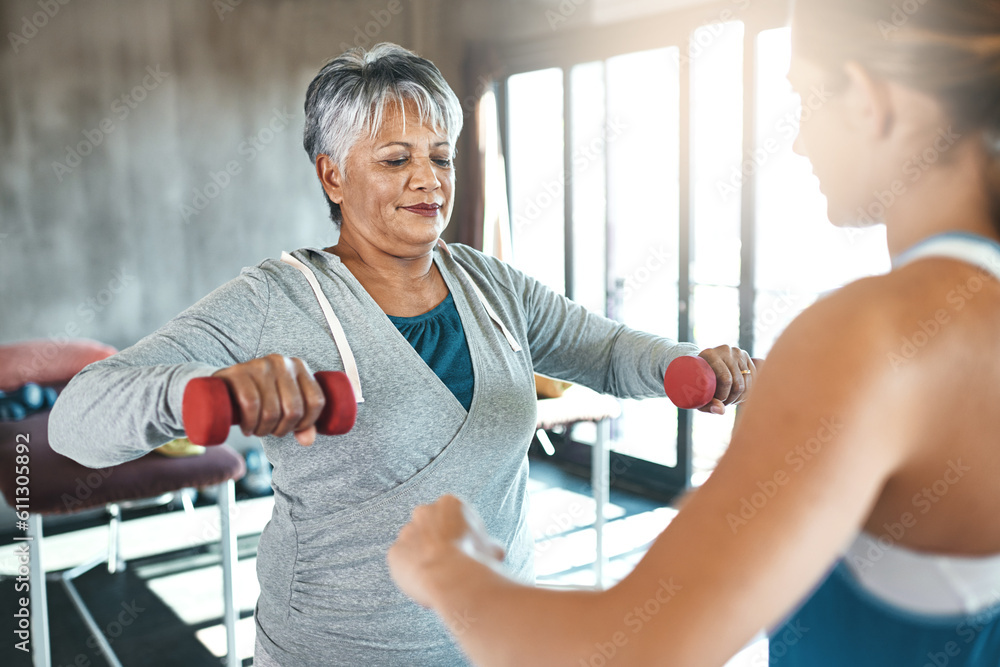 Woman training with dumbbells guided by personal trainer in warm studio